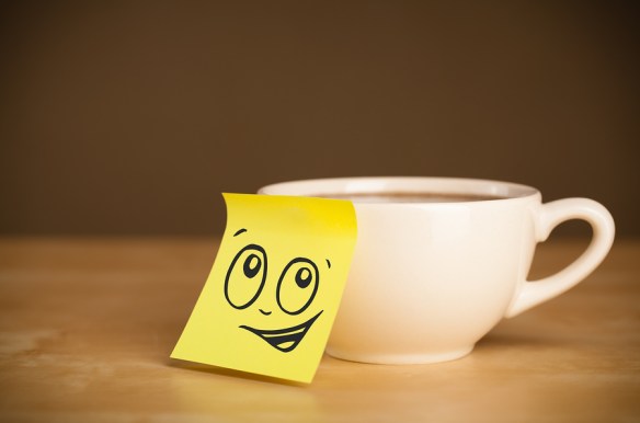 Drawn smiley face on a post-it note sticked on a cup